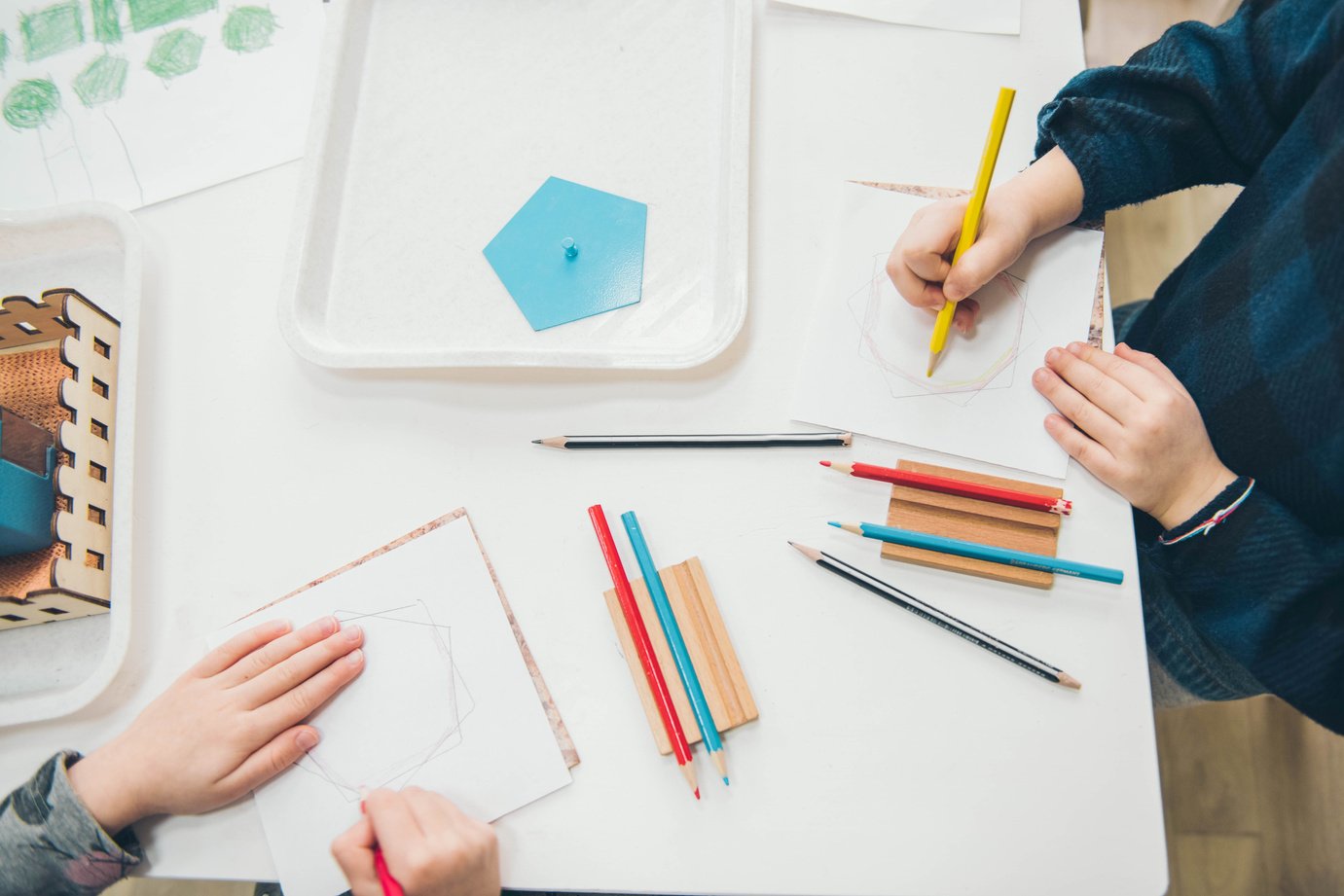 Montessori School. Learning materials in a montessori methodology school. Geometric materials. Color pencils. Little girls drawing on paper.